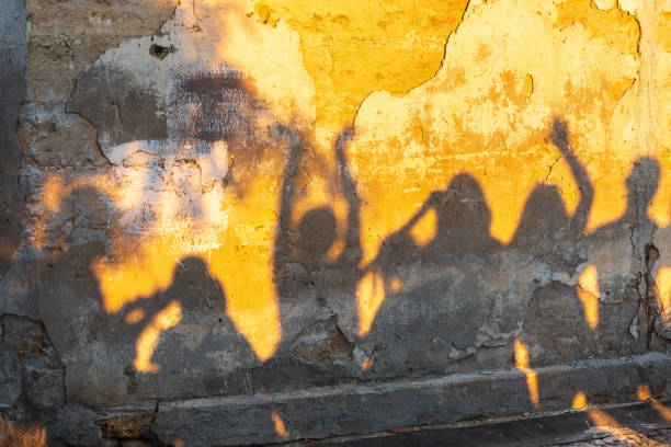 istock Shadows of dancing people on an old stone wall at sunset time. 1418838661