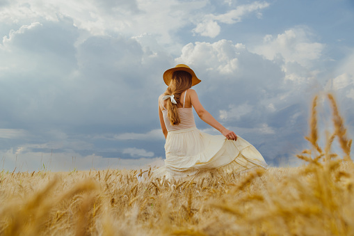 Woman in rural dress and hat dancing alone in wheat field
