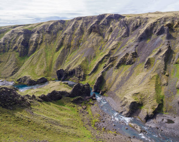 istock View on river stream and green moss covered cliffs and hills in Eldgja gorge in Iceland, grass bank, blue sky 1418840171