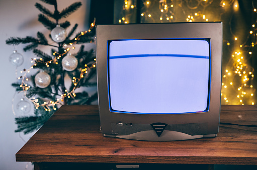Retro TV set with glitch effect in a room with Christmas decorations on wooden table