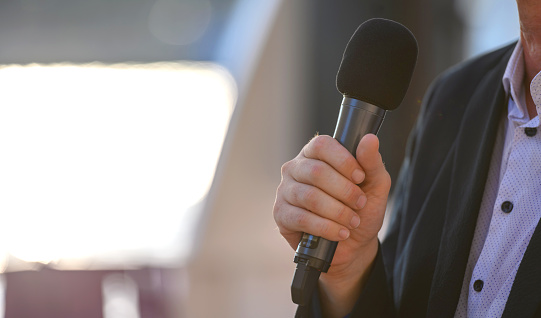 Unrecognizable male public speaker holding a microphone