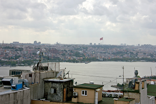 Balat, eminönü and karaköy view, there are lots of people on the bridge, lots of them are fishing, and beyond the bridge you see the golden horn view with ottoman mosques in a cloudy summer day.