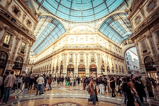 Milano, Italy - February 12, 2022: People visiting the upscale shopping lane Galleria Vittorio Emanuele II in Milano. Extremely expensive shops, restaurants attracts also visitors, tourists...