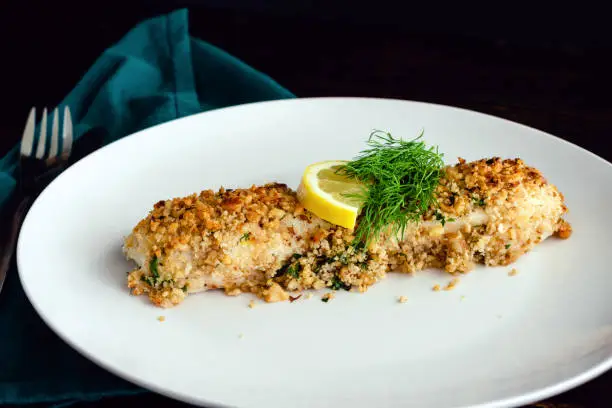 Baked white fish fillet garnished with fresh dill and a slice of lemon