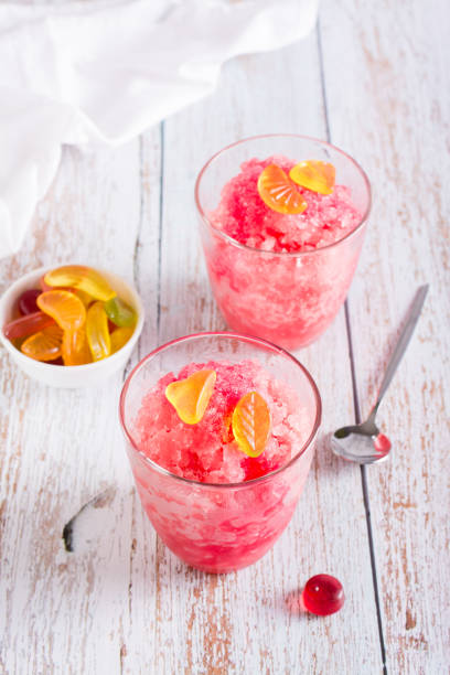 istock Red shaved ice snow cone with syrup and sweets in glasses on the table. Vertical view 1418845664