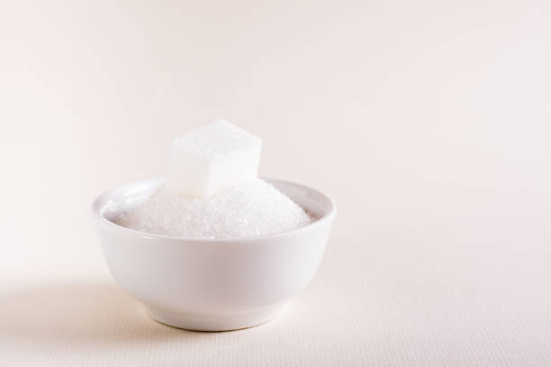 istock Bowl with granulated sugar and a cube on a pink background. Choosing between types of sugar 1418845684