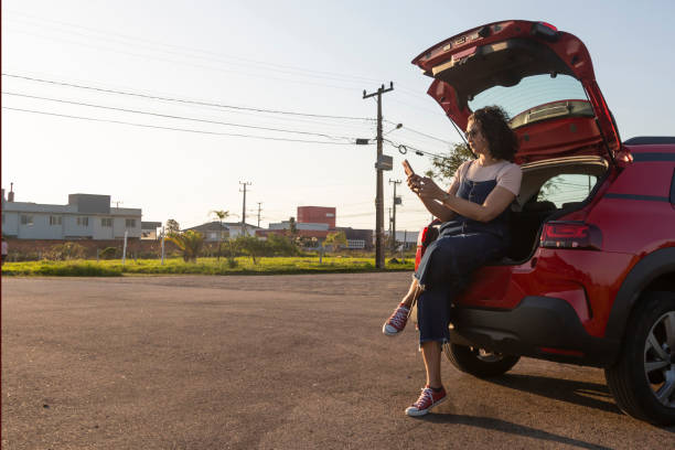 istock Latin woman doing selfie sitting in car trunk 1418846906