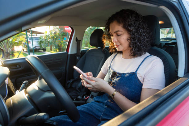istock Latin woman using cellphone in parked car 1418846989