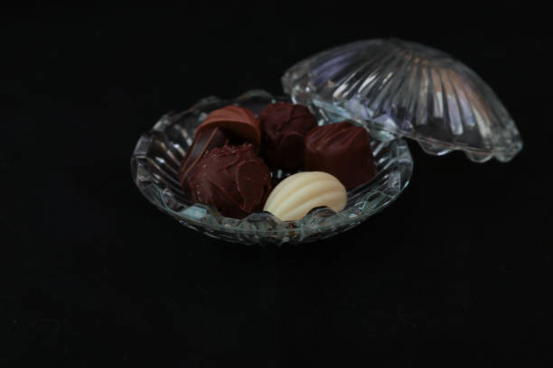 istock Chocolates in a glass bowl isolated on a black background. 1418847879