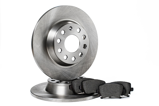 Two new brake discs and a set of brake pads stacked in a row on a white background. isolated items.