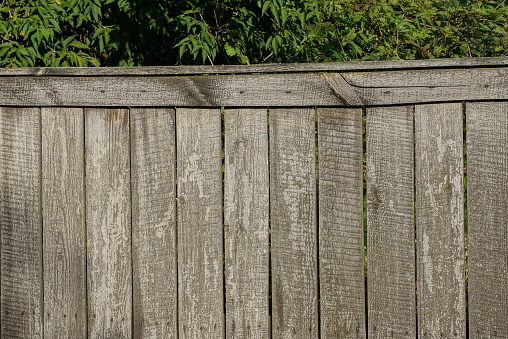 part of a gray rural fence wall from wooden boards on the street