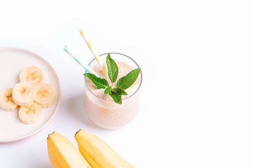 Banana smoothie with ingredients on white background. Top view, copy space.