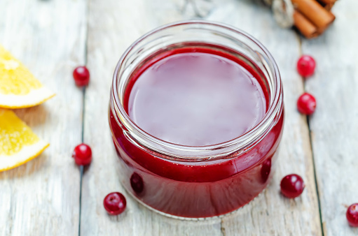 Orange cinnamon honey cranberry sauce in a jar on a wood background. toning. selective focus