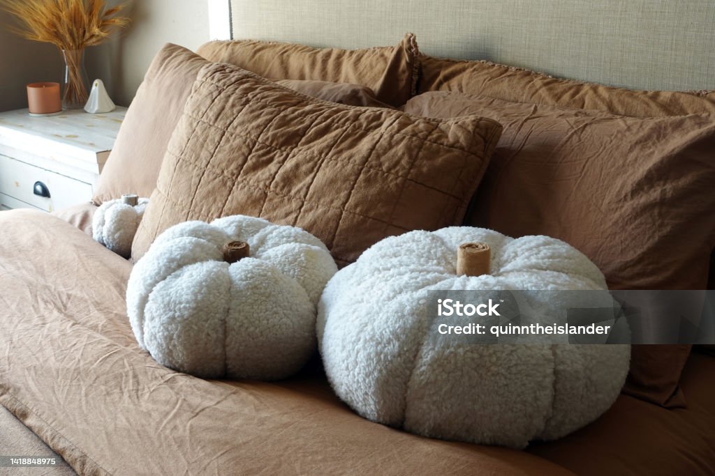 Warm Brown Halloween Bedroom Decor Stuffed, white DIY pumpkins made of Sherpa fabric on a warm brown bed set Decoration Stock Photo