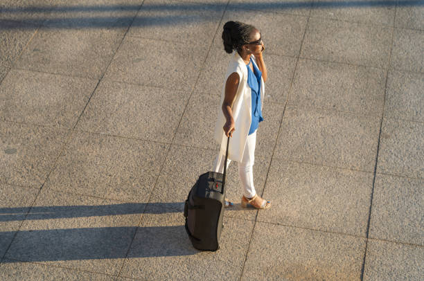 blurred motion of Businessman on cell phone checking the time walking on footpath,handbag with suitcase on foreground.