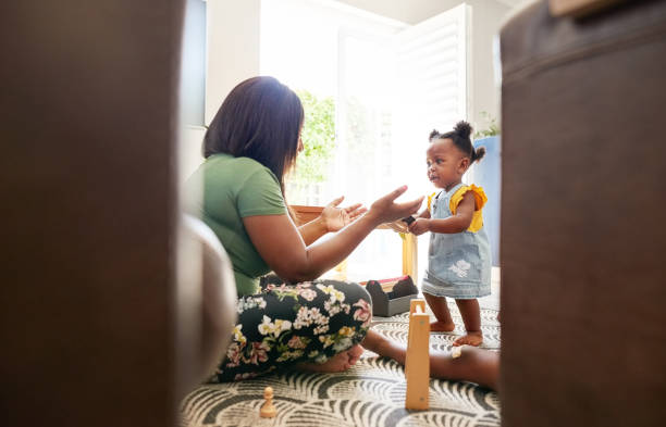 istock Mother helping her daughter learn to walk at home 1418850306