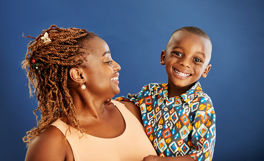 Close-up portrait of a smiling young woman with her son against blue background