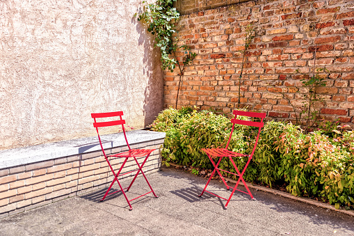 Murano, Italy - July 7, 2022: Two red chairs in the corner of a park in Murano Italy