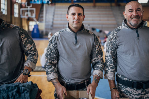 Group of people, soldiers on humanitarian aid preparing donations for civilians in school gymnasium, after natural disaster happened in city.