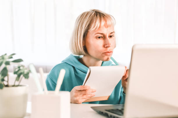 istock Woman watching on laptop display and writing notes. Video call, online conference, webinar 1418853561