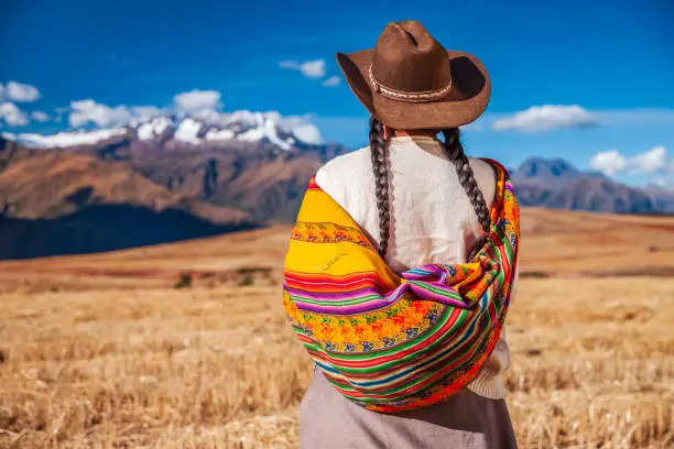 Peruvian woman in national clothing admiring view of Andes in The Sacred Valley. The Sacred Valley of the Incas or Urubamba Valley is a valley in the Andes  of Peru, close to the Inca  capital of Cusco and below the ancient sacred city of Machu Picchu.