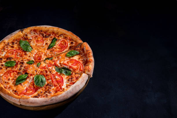istock Delicious fragrant pizza-Margherita with mozzarella, tomatoes and basil on tomato sauce on black background. Copy space 1418863949