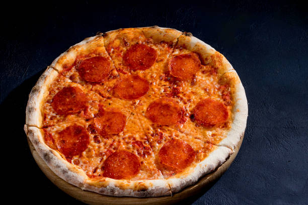 istock Pizza with tomato sauce, mozzarella, salami on black background. View from above, copy space. 1418864002