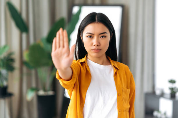 chinka pokazuje do kamery gest stop. walka o prawa wyborcze kobiet i równość płci, przeciwko przemocy domowej, wojnie i rasizmowi rasowemu, stojąc w domu - protest stop gesture stop sign no zdjęcia i obrazy z banku zdjęć