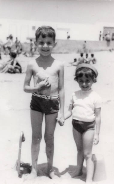 Vintage image from the sixties, a little boy and a little girl posing together smiling at the beach stock photo