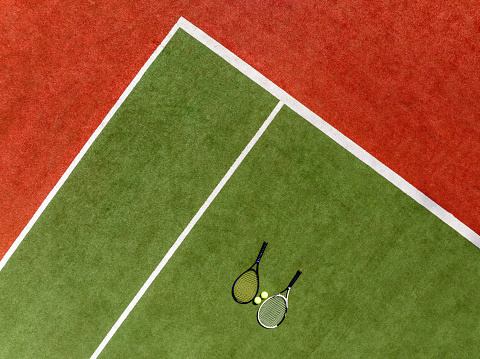 Overhead aerial view of a synthetic tennis court and tennis rackets and balls