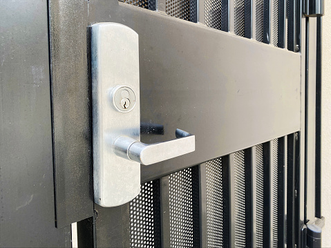 Woman's hand puts the key in the keyhole of the office door. Home security concept