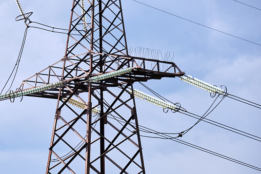 High voltage tower with electric power lines divided by safe guard bushing transfening safely electrical energy through cable wires. Electricity transmission on long distance concept.
