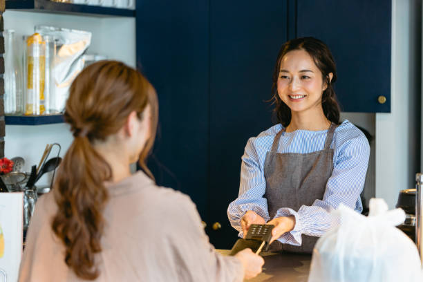 istock woman who makes a smartphone payment at a cafe (restaurant / takeout) 1418919897