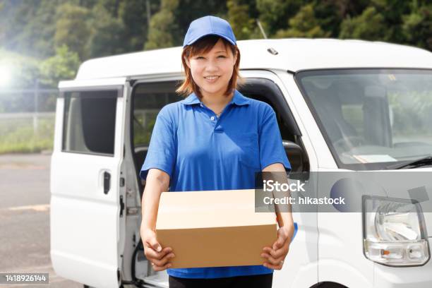 Woman In Blue Polo Shirt And Hat Carrying Cardboard Boxes She Works As A Mover And Courier Stock Photo - Download Image Now
