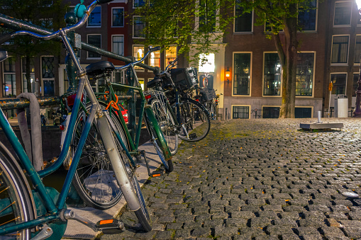 Netherlands. Summer night in Amsterdam. Bicycles is parked at the canal fence and secured with an anti-theft chains