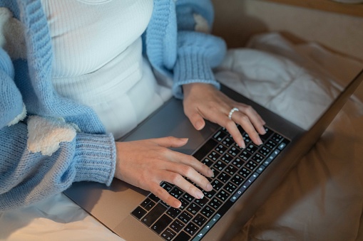 Asian female tourist using laptop to work at night during her solo trip in the campervan.