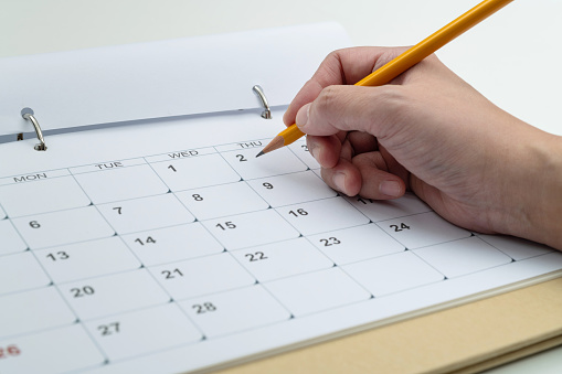 Woman Hand With Pencil Writing On Calendar Page Stock Photo - Download