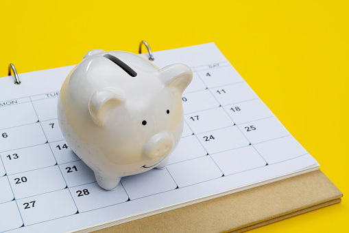 Calendar and piggy bank on yellow background.
