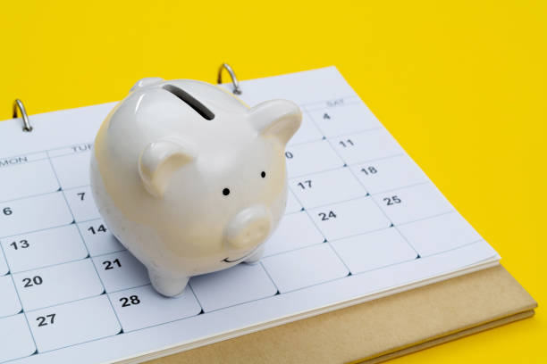 Calendar and piggy bank on yellow background stock photo