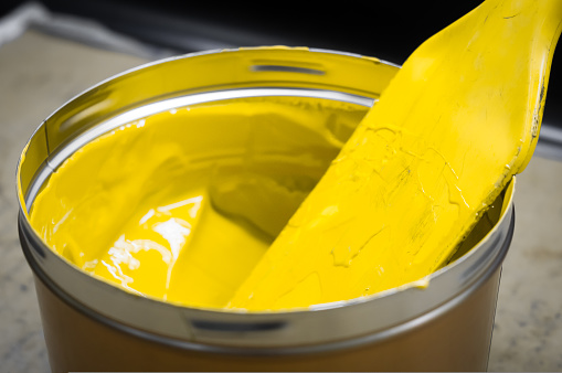 A can of yellow polygraph offset paint for the printing press. Special UV ink for printing. Open new can of yellow paint. Selective focus.