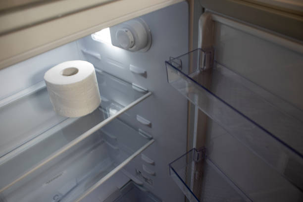 istock Empty Refrigerator. Toilet Paper in an Empty Refrigerator. White Open Refrigerator. 1418941631