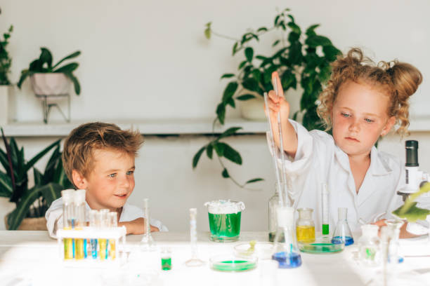 Serious little boy and girl in white uniforms conducting chemical experiments in a laboratory.Back to school concept.Young scientists.Natural sciences.Preschool and school education of children stock photo