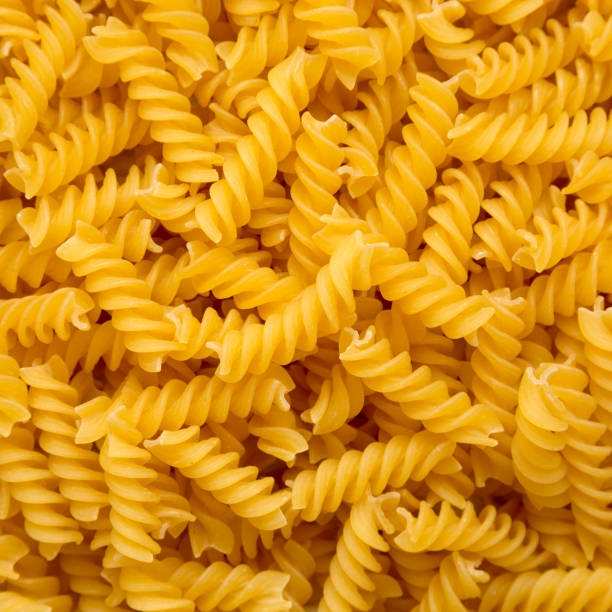 istock Uncooked Yellow Organic Rotini Pasta, overhead view. Flat lay, top view, from above. Close-up. 1418943156