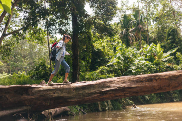 istock woman balancing and walking on tree trunk over river 1418944396