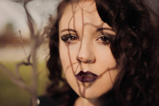 Young woman headshot portrait with bare tree branches shadows on her face