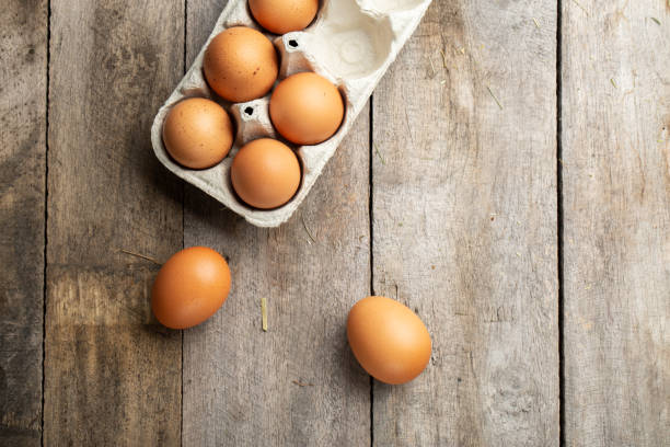 œufs de poule biologiques frais en carton ou en contenant d’œufs sur fond de bois. agriculture et concept agricole. - protein isolated shell food photos et images de collection