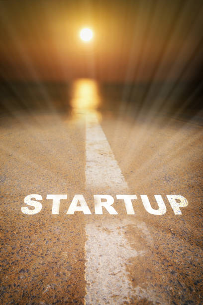 istock Startup written on road surface with white marking line leading into abstract blur sunlight and sun 1418955473