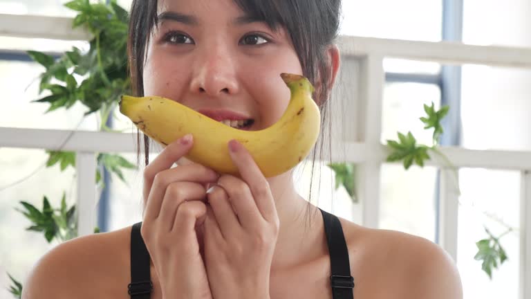 Banana Healthy eating young woman workout holding organic banana fruit healthy lifestyle. Wellness Asian women use yellow banana smile face look at camera. Beautiful healthcare nutrition lifestyle