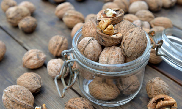 closeup on walnuts in a glass jar among others on wooden table closeup on walnuts in a glass jar among others on wooden table brain jar stock pictures, royalty-free photos & images