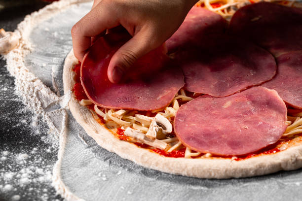 istock Making a pizza laying out the ham on the dough 1418961541